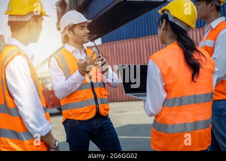 Business Logistics Concept, Foreman Control caricamento contenitori scatola di carico nave per la pianificazione logistica e spiegare il lavoro al team di diversità Foto Stock