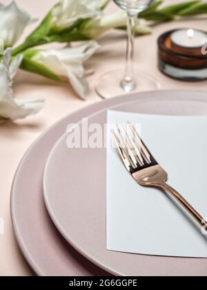Tavolo da matrimonio. Biglietto d'invito per la festa bianca con fiore di gladiolo bianco e candela sullo sfondo. Foto Stock
