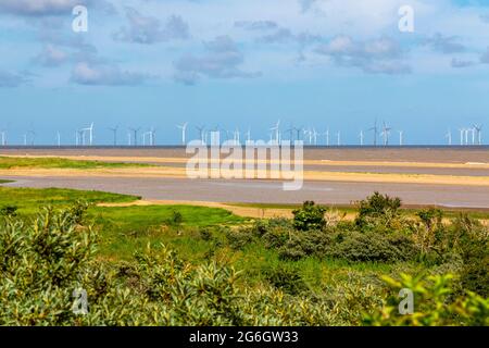 Lincs Offshore Wind Farm Turbines visto dalla costa vicino Skegness nel Lincolnshire Inghilterra Regno Unito con la spiaggia in primo piano. Foto Stock