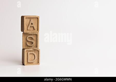 Foto sul tema ASD (disturbi dello spettro autistico). Cubi di legno con l'abbreviazione 'ASD', su sfondo bianco. Foto con spazio per il testo Foto Stock