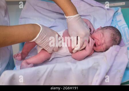 Pannolino per medicazione un neonato da un medico immediatamente dopo il parto Foto Stock