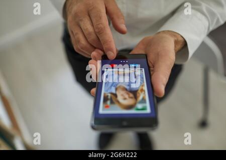 Uomo che usa uno smartphone per scorrere i profili delle donne e premere un pulsante del cuore con il dito. Foto Stock