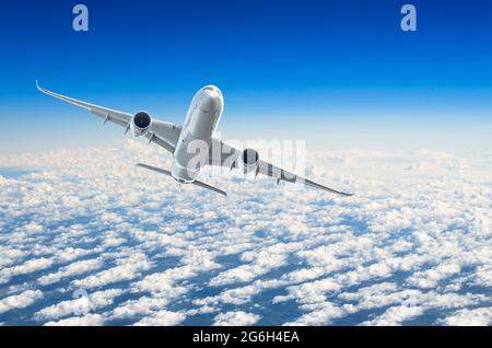 L'aereo passeggeri vola a livello di volo sullo sfondo di nuvole e di un cielo blu Foto Stock