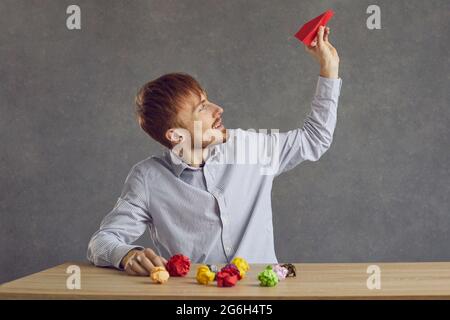 Il giovane con la barba fece un aereo rosso di carta, dopo diversi tentativi falliti, puntò la mano. Foto Stock