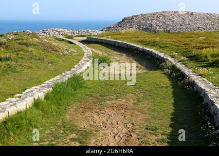 Un basso muro di pietra fiancheggiato tortuoso percorso attraverso la terra pubblica vicino al mare Suances Cantabria Spagna Foto Stock