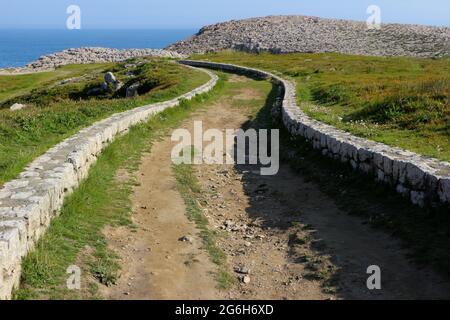 Un basso muro di pietra fiancheggiato tortuoso percorso attraverso la terra pubblica vicino al mare Suances Cantabria Spagna Foto Stock