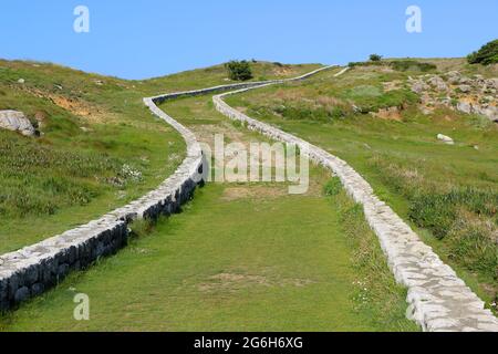 Un basso muro di pietra fiancheggiato tortuoso percorso attraverso la terra pubblica vicino al mare Suances Cantabria Spagna Foto Stock