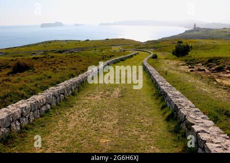 Un basso muro di pietra fiancheggiato tortuoso percorso attraverso la terra pubblica vicino al mare Suances Cantabria Spagna Foto Stock