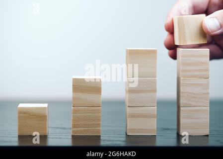 primo piano di mano di persona impilando blocchi di legno, crescita economica e business successo concetto Foto Stock