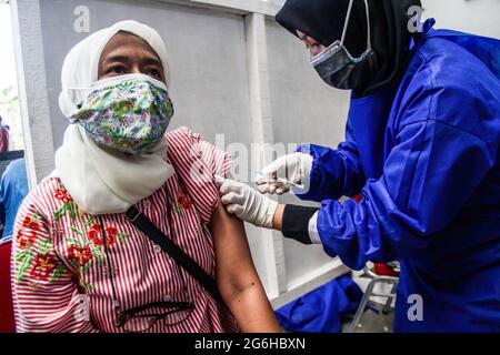 Bandung, Indonesia. 06 luglio 2021. Una donna riceve una dose del vaccino Covid-19 al mercato moderno Sarijadi a Bandung. Il Ministro della Sanità Budi Gunadi Sadikin ha detto che il Ministero della Salute (Kemenkes) continuerà a incrementare il tasso di vaccinazione per il coronavirus (Covid-19) a 5 milioni di dosi al giorno. Credit: SOPA Images Limited/Alamy Live News Foto Stock