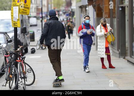 Londra, Inghilterra, Regno Unito. Uomo che guida uno skateboard sul marciapiede Foto Stock