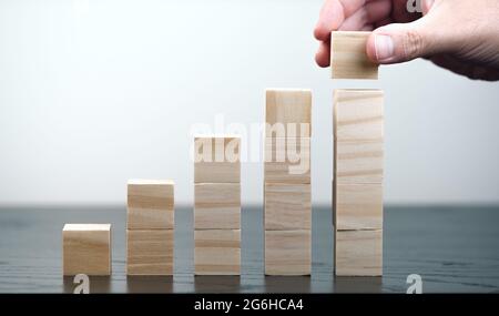 primo piano di mano di persona impilando blocchi di legno, crescita economica e business successo concetto Foto Stock