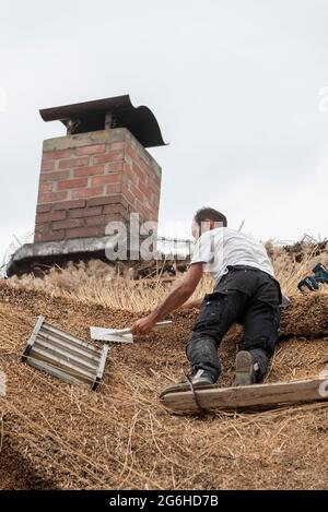 Hiddensee, Germania. 25 Giugno 2021. Un tatcher rinnova il tetto di una vecchia casa di pescatori a Vitte. Credit: Stefano Nosini/dpa-Zentralbild/ZB/dpa/Alamy Live News Foto Stock