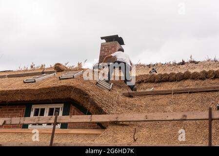 Hiddensee, Germania. 25 Giugno 2021. Un tatcher rinnova il tetto di una vecchia casa di pescatori a Vitte. Credit: Stefano Nosini/dpa-Zentralbild/ZB/dpa/Alamy Live News Foto Stock