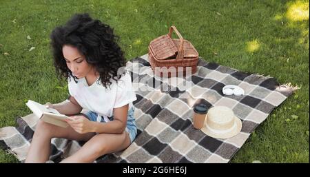 vista dall'alto del libro di lettura della donna afroamericana durante il picnic Foto Stock