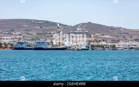 Isola di Antiparos Cicladi, Grecia. 25 maggio 2021. Ormeggiato traghetto al porto, bianchi edifici tradizionali saliti sulle colline, Mar Egeo calma scintillante bl Foto Stock