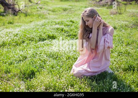 Bella donna bionda raccoglie fiori in giardino fiorito in primavera Foto Stock