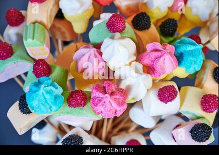 Dolci a base di marshmallows e altre prelibatezze su spiedini di legno disposti come un bouquet di fiori. Foto Stock