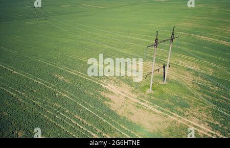 Torri di linea elettrica ad alta tensione su un'antenna verde di sfondo prato sopra la vista dall'alto Foto Stock