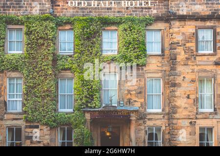 Buxton, Regno Unito - Giugno 26 2021: La grande facciata in pietra decorata con edera verde dello storico Old Hall Hotel nella città mercato di Buxton, Derbyshire, en Foto Stock