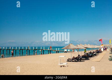 Antalya, Turchia-29 giugno 2021: Persone che camminano sul molo e sulla costa, nuotare e prendere il sole sulla spiaggia in estate ad Antalya. Foto Stock