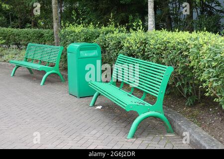 Panchine in metallo verde nel parco per la ricreazione dei visitatori Foto Stock