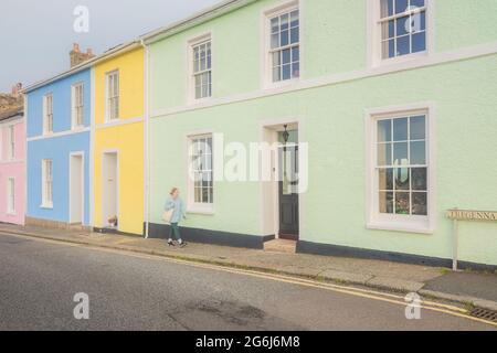 Una giovane donna bionda cammina lungo colorati edifici residenziali nella pittoresca città vecchia storica del pittoresco villaggio balneare di St Ives Foto Stock