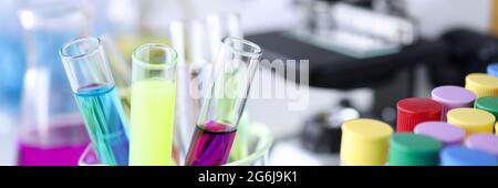 Provette per analisi chimiche con liquidi multicolore sullo sfondo del microscopio Foto Stock