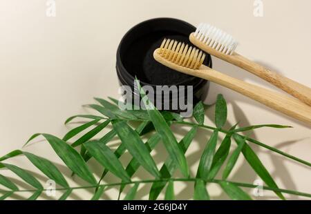 Un set di spazzolini eco-friendly di bambù e polvere nera del dente su uno sfondo beige pastello. Stile di vita sostenibile e senza sprechi. Concetto privo di plastica Foto Stock