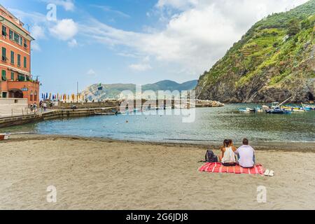 Vernazza, Italia - 21 giugno 2021: Coppia seduta tutta da sola alla spiaggia del villaggio Vernazza nelle cinque Terre. Foto Stock
