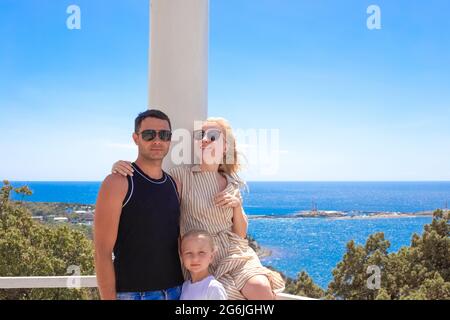 Bella giovane famiglia papà, mamma e figlia sul lungomare. Viaggi estivi e turismo, buon fine settimana. Foto Stock