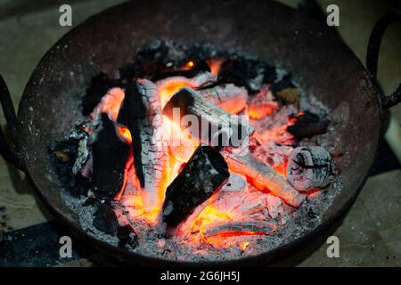 Carbone che brucia in una stufa di ferro per il riscaldamento domestico. Carbone rosso bruciato e ceneri per riscaldare la stanza. Foto Stock