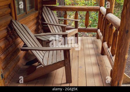 Sedie Adirondack in legno sul portico di rustica cabina di tronchi Foto Stock