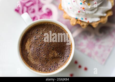 caffè appena preparato in tazza, accanto a un cestino per torte con crema proteica, un buon inizio di giornata, un delizioso dessert Foto Stock