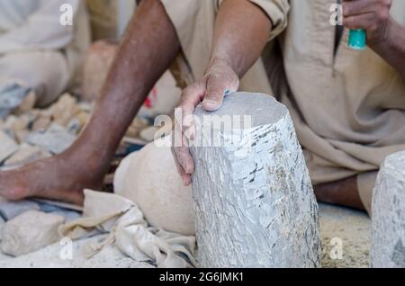 Mani di uno scultore egiziano maschile mentre si lavora con un alabastro in pietra da vicino Foto Stock