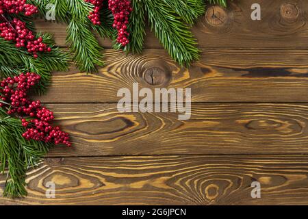 Sfondo di Natale. Rami di abete nobilis, rametti con bacche rosse su tavole di legno marrone. Spazio di copia, disposizione piatta, vista dall'alto. Vacanze, Natale, Capodanno con Foto Stock