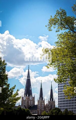 Guglie di Tulsa con edifici moderni e vecchi incorniciati da alberi sotto un bel cielo blu con nubi soffici Foto Stock