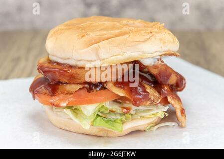 Panino di pollo al barbecue che gocciola con salsa piccante lungo tutti i buoni ripieni di hamburger tra i panini. Foto Stock