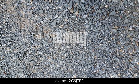 Ghiaia di granito, pietre, pietra frantumata primo piano. Trama ruvida senza cuciture, fondo del materiale da costruzione. Foto Stock