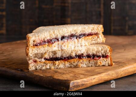 Un panino di gelatina di burro di arachidi e uva su un tagliere di legno Foto Stock