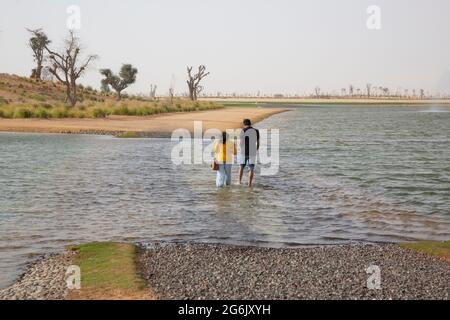 Una coppia attraversa l'acqua presso i Love Lakes di al Qudra, Dubai, Emirati Arabi Uniti. --- i laghi d'amore di Dubai sono costituiti da due laghi artificiali a forma di cuore. Il l Foto Stock