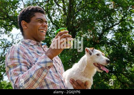 Uomo sorridente che tiene Jack Russell terrier cane e caffè per andare Foto Stock