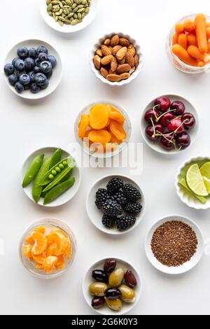 Vista dall'alto di piccoli piatti ripieni di vari ingredienti biologici sani, su sfondo bianco. Foto Stock