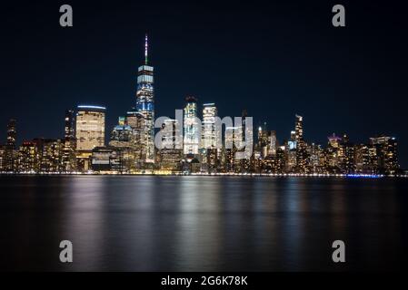 Lower Manhattan dal New Jersey sul fiume Hudson e tutti gli alti raschiatori del cielo di notte Foto Stock