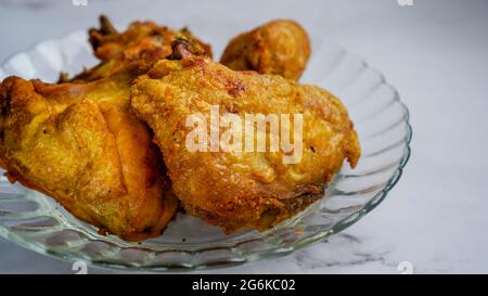 Ayam goreng kunyit o pollo fritto curcuma, pollo fritto e stagionato con curcuma e sale. Foto Stock