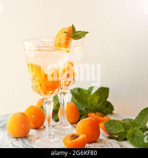 Bevande estive, cocktail di albicocche alla menta con ghiaccio in bicchieri. Rinfrescanti cocktail estivi alcolici o non alcolici fatti in casa o infusi Detox aromatizzati Foto Stock