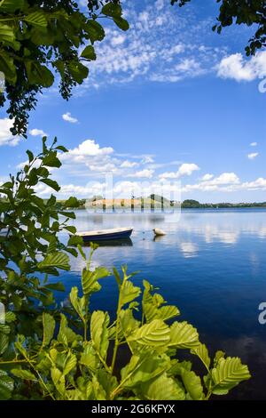 Bella vista su un lago di Białe (distretto del lago di Kaszuby) visto attraverso l'albero. Piccola imbarcazione che galleggia su una superficie di acqua pulita. Foto Stock