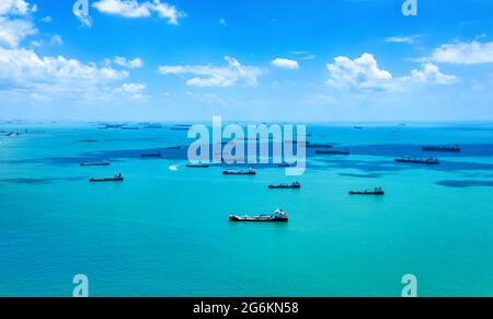 Vista aerea delle navi portacontainer nello stretto di Singapore. Aereo sparato. Navi da carico ancorate alla strada, in attesa di entrare nel porto più trafficato della regione. Foto Stock