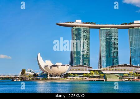 Vista iconica di Marina Bay Sands, centro commerciale Shoppes, museo ArtScience, ponte di Helix a Marina Bay in giornata di sole. Famosi punti di riferimento della città-stato di Singapore. Foto Stock