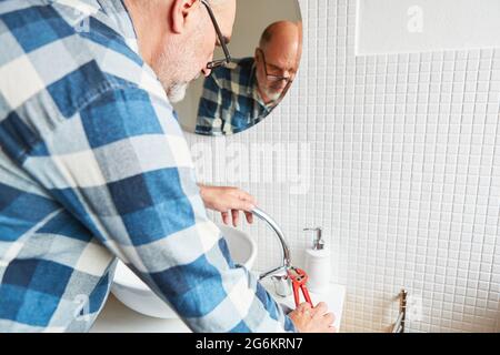 Idraulico o manuale assembla lavello rubinetto in bagno con chiave a tubo Foto Stock